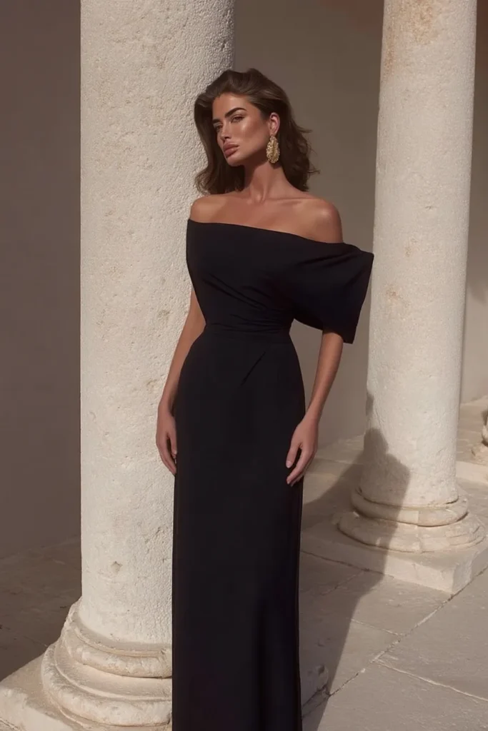 Glamorous black cocktail dress wedding guest option with sweetheart off-shoulder neckline, short structured sleeves, fitted waist, and floor-length silhouette