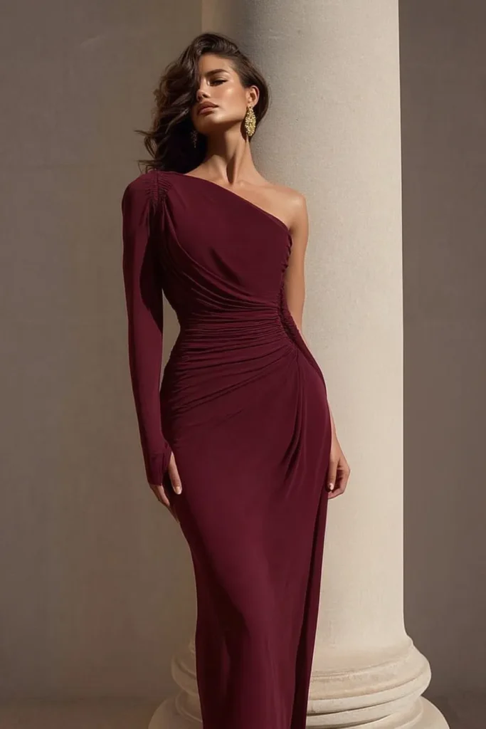 Glamorous burgundy wedding guest dress with one-shoulder design, off-shoulder styling, gathered fabric at the waist, body-hugging fit, and floor-length hemline, perfect for upscale wedding events
