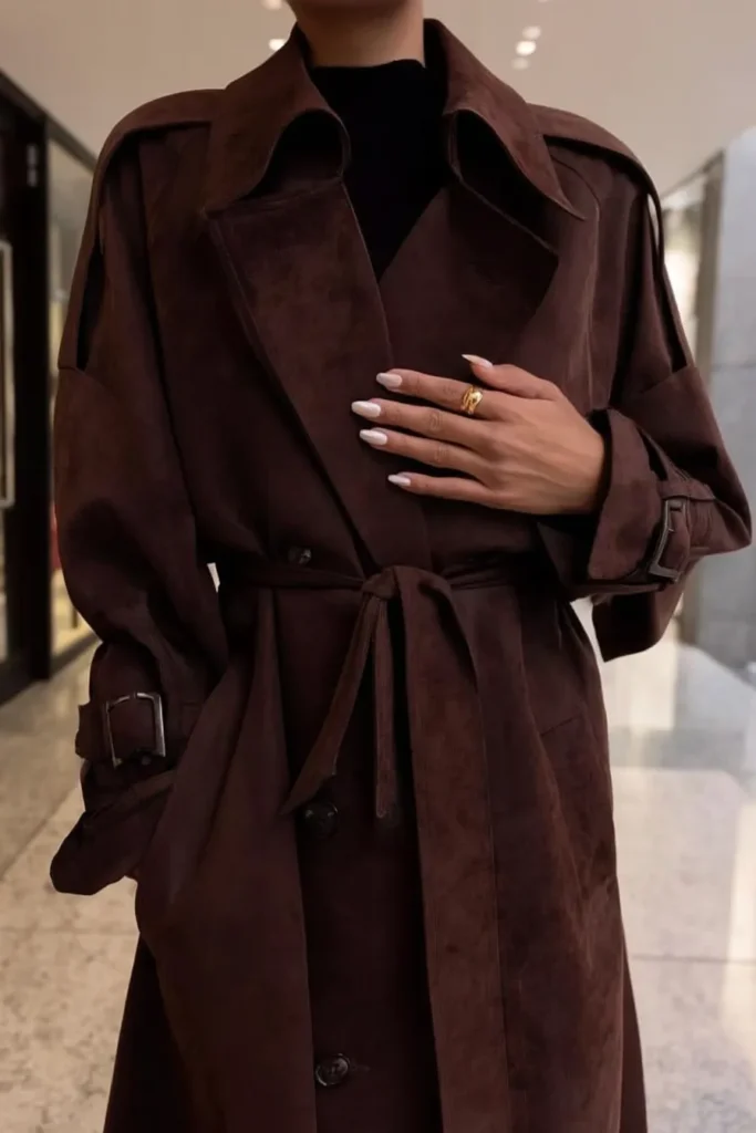 Chic fall winter outfits, tailored brown trench coat, black turtleneck base layer, gold rings, and polished manicure creating timeless autumn winter fashion outfit