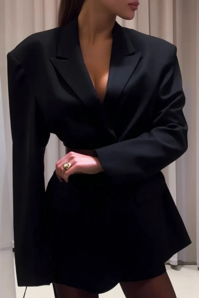Chic fall work outfits for women, with elegant black blazer worn as dress, tied with coordinating black belt and gold statement ring for seasonal corporate wardrobe goals