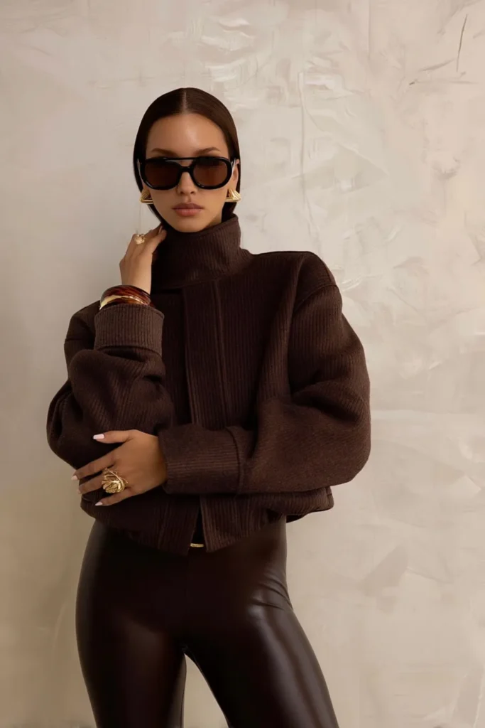Chic stylish winter outfits brown coat, fitted ribbed knit turtleneck, and high-waisted leather trousers. Tonal layering in warm earth tones creates seasonal fashion.