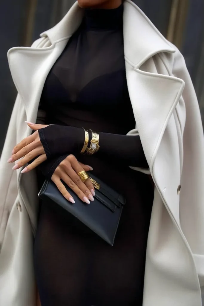 Fall winter outfits, elegant outfit with cream oversized wool coat layered over black turtleneck dress, and sleek black leather clutch bag for sophisticated cold weather styling