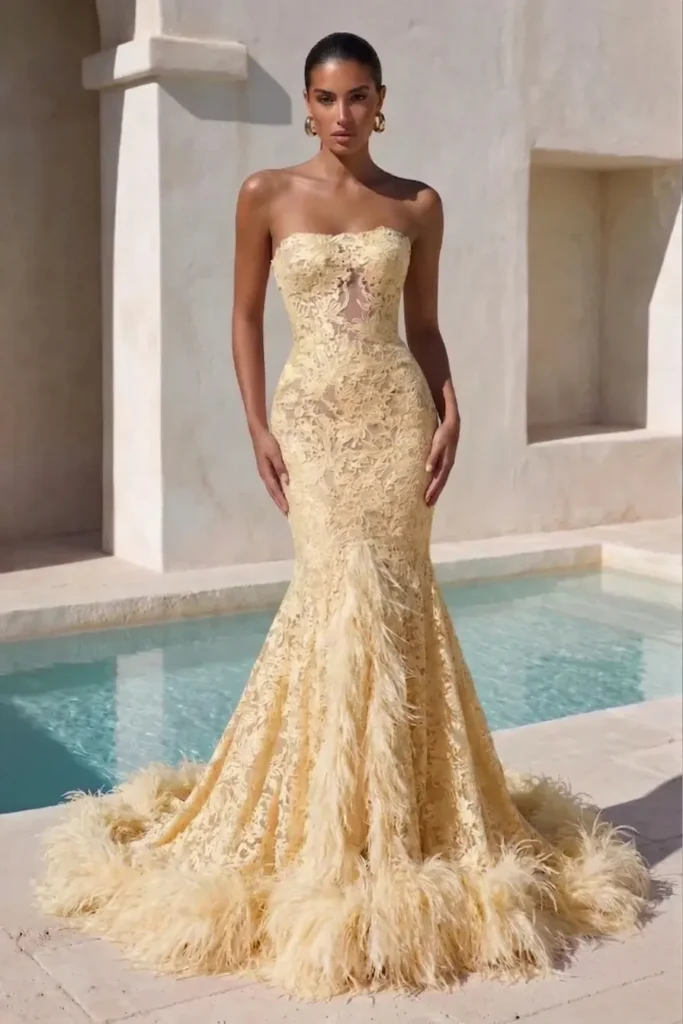 Butter yellow elegant wedding guest dress, strapless sweetheart neckline, floral lace overlay, mermaid silhouette, feather-trimmed hem, with gold  earrings for glamorous formal elegance